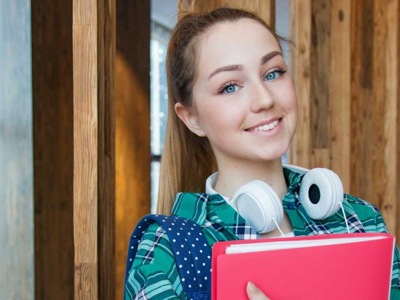 Woman Standing in Hallway While Holding Book