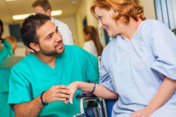 Female patient in wheelchair being assisted by male nurse