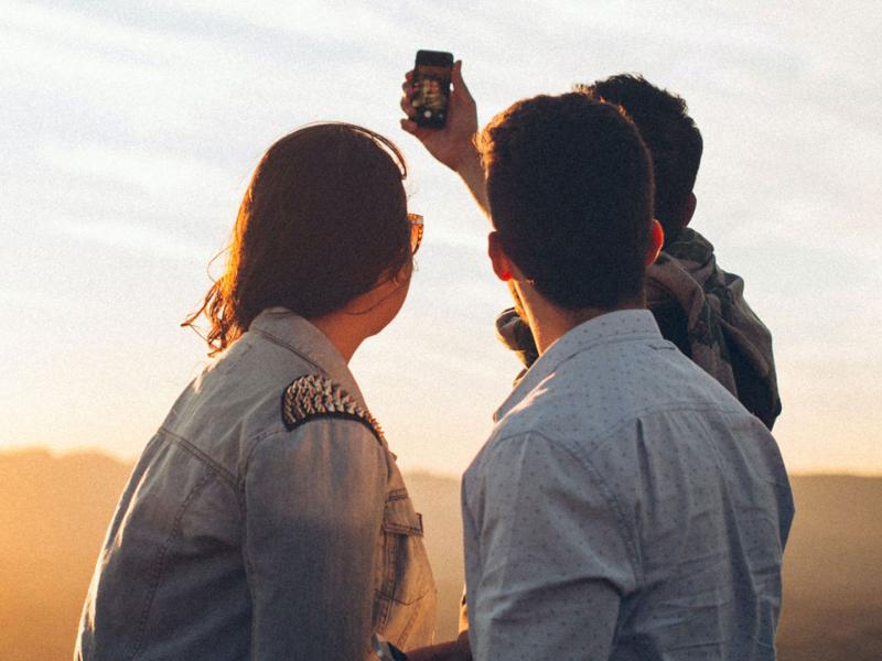 Four Person Standing at Top of Grassy Mountain