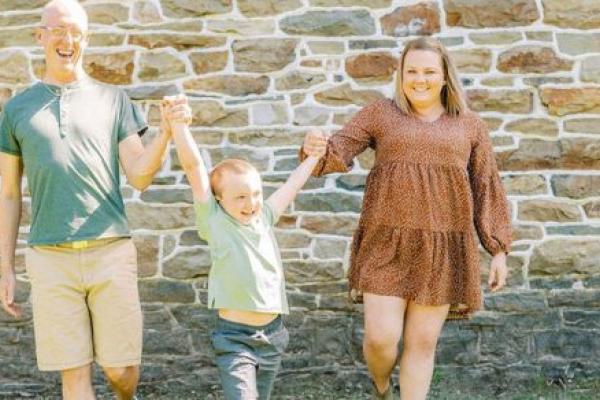 Two young parents and their young child outside smiling