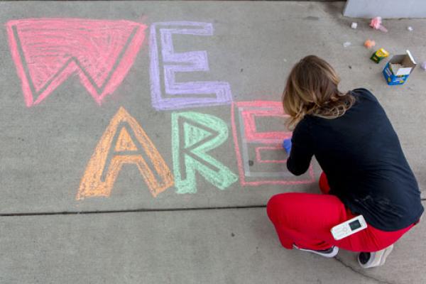 Female drawing on a sidewalk with chalk.