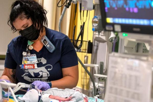 A young registered nurse women taking care of a baby in the NICU
