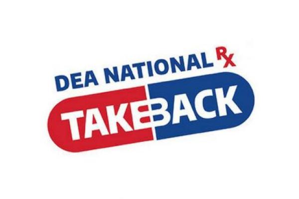 Six people - five wearing high-visibility vests, one wearing a police uniform - stand in front of the building.