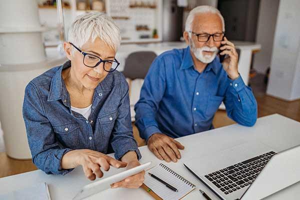 Senior man and woman reviewing billing statements, while man is on the phone.