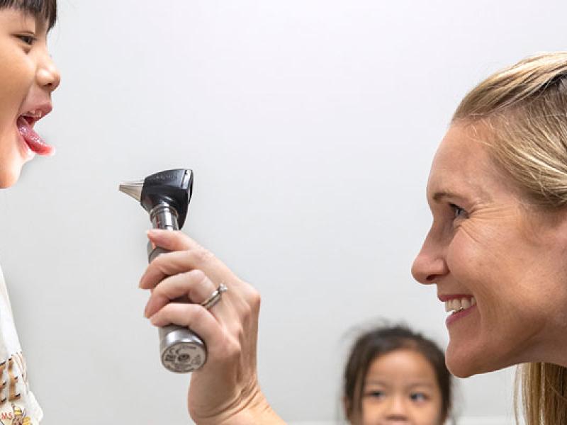 Female provider examining a young patient on exam table.