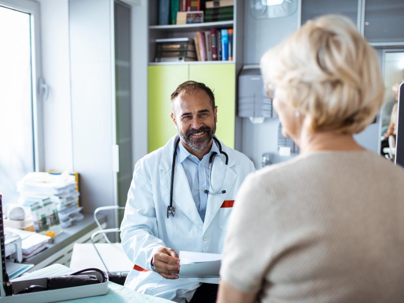 A physician smiles with patients. Learn more about physician jobs with Penn State.