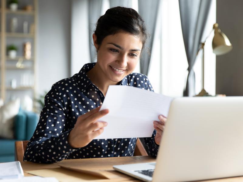 A woman looks at her new hire paperwork and smiles.