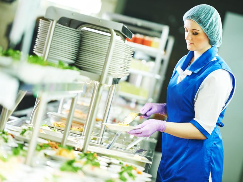 A cafeteria worker preps a station.