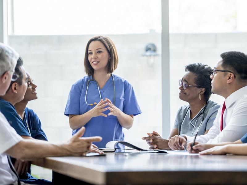 A health care faculty professional speaks to a room of peers.