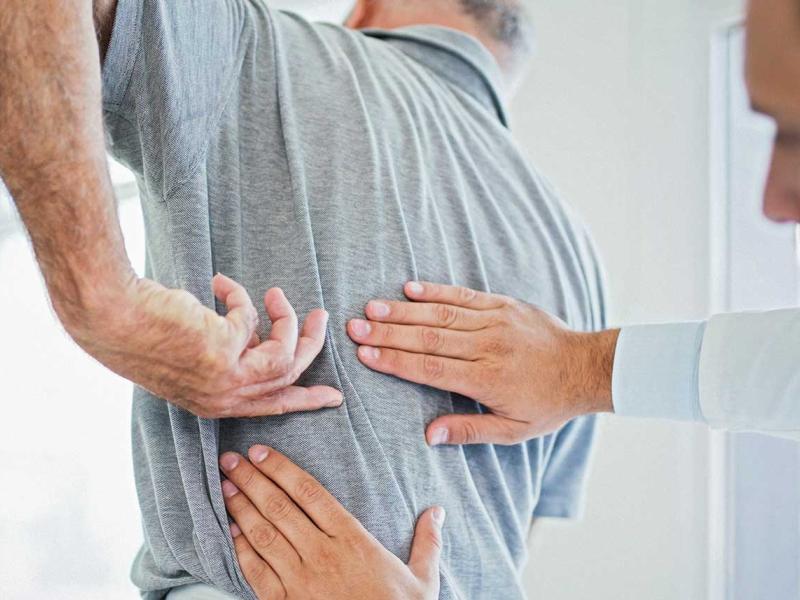 Male doctor examines a male patient's back