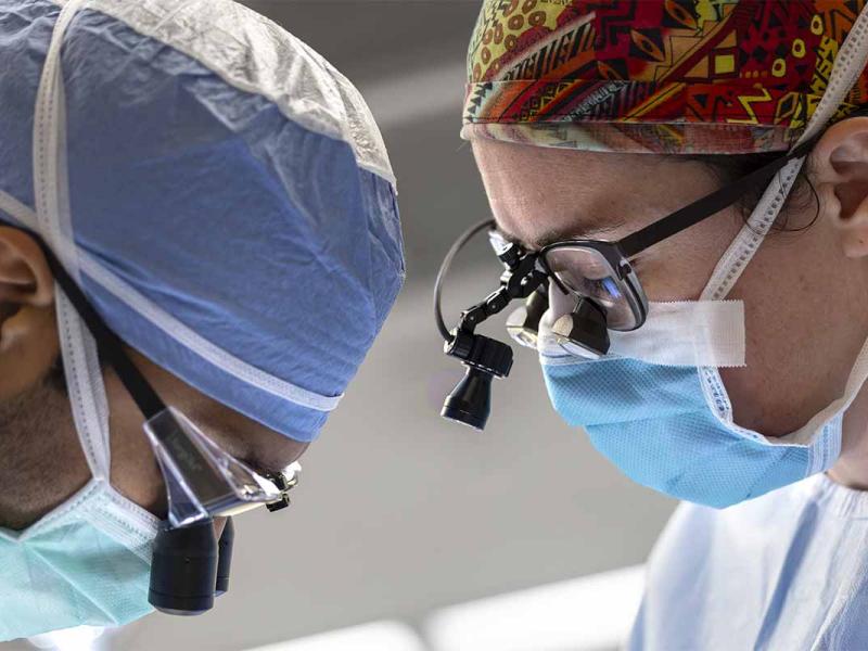 Two surgeons perform surgery on a patient. 
