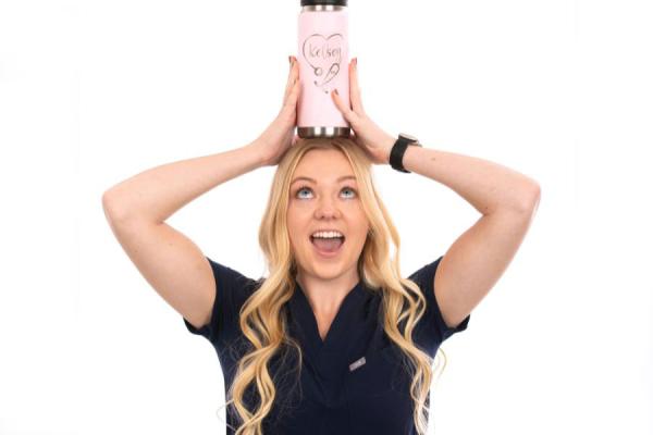 Young female posing with a water bottle on top of her head smiling.