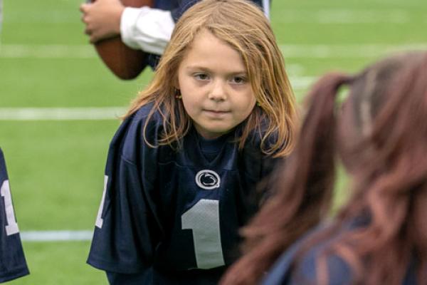 Young child on a football field wearing a dark blue jersey.