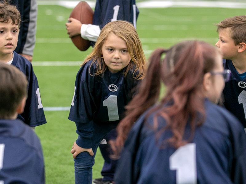 Young child one a football field in a dark blue jersey.