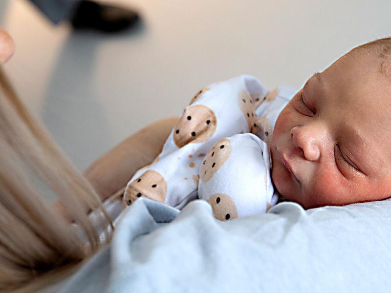 Newborn infant sleeping in the arms of a woman.