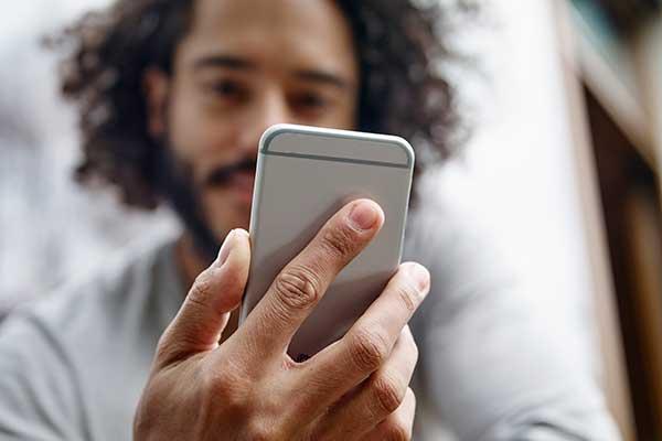 Close up of a young man's hand holding a mobile phone.