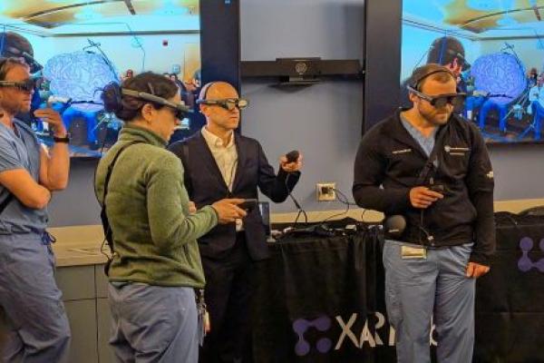neurosurgeons and neurosurgery residents are wearing headseats and holding remote controls to join a remote, mixed reality case review