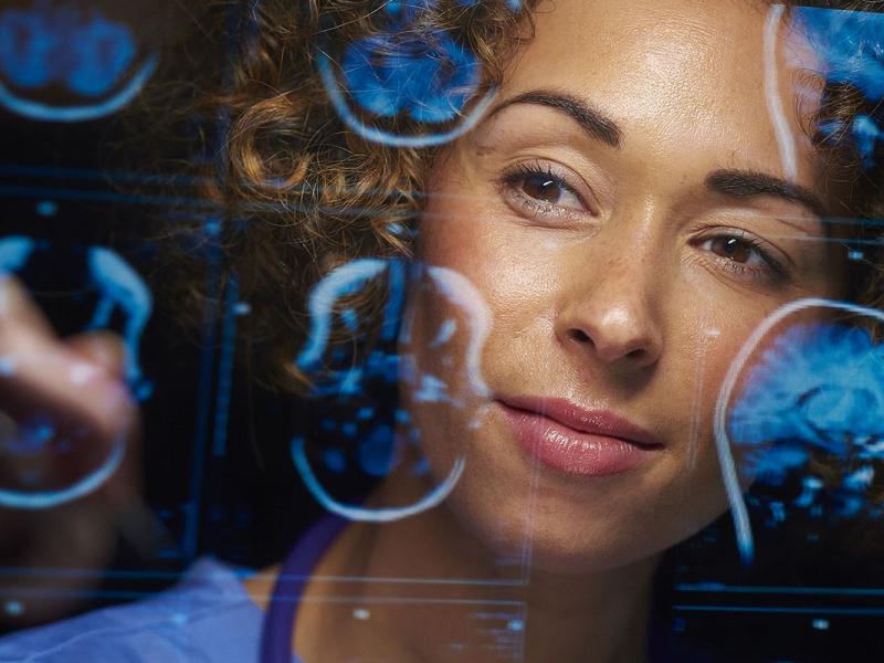 a female doctor or surgeon is analyzing the digitally generated scans  of a human brain.