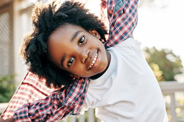 Portrait of a cheerful little boy playing around while looking into  the camera outside during the day.