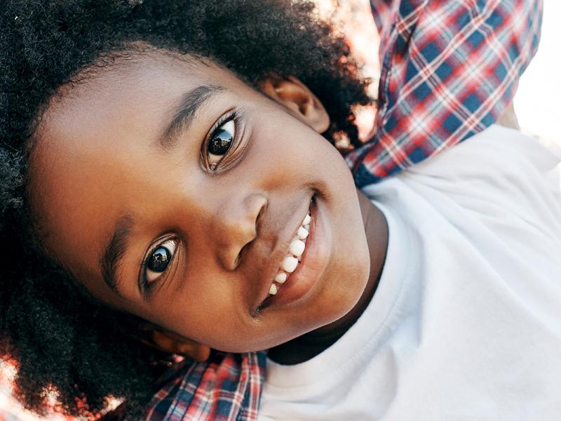 Portrait of a cheerful little boy playing around while looking into the camera outside during the day.