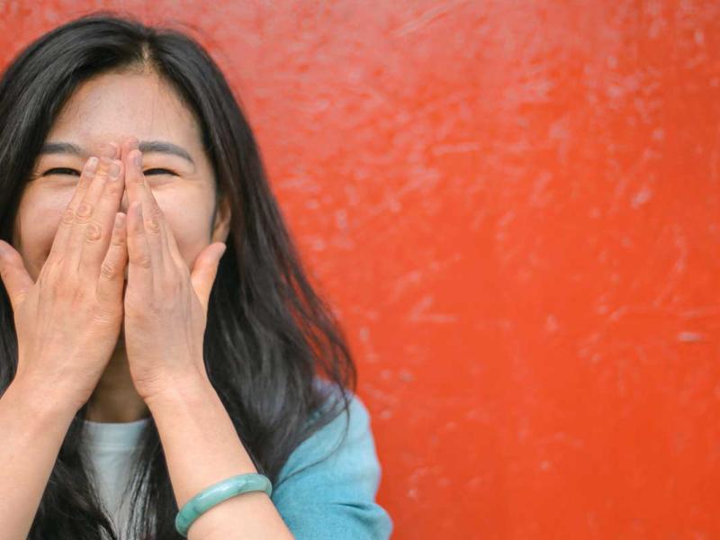 Cheerful ethnic woman against vivid red painted wall