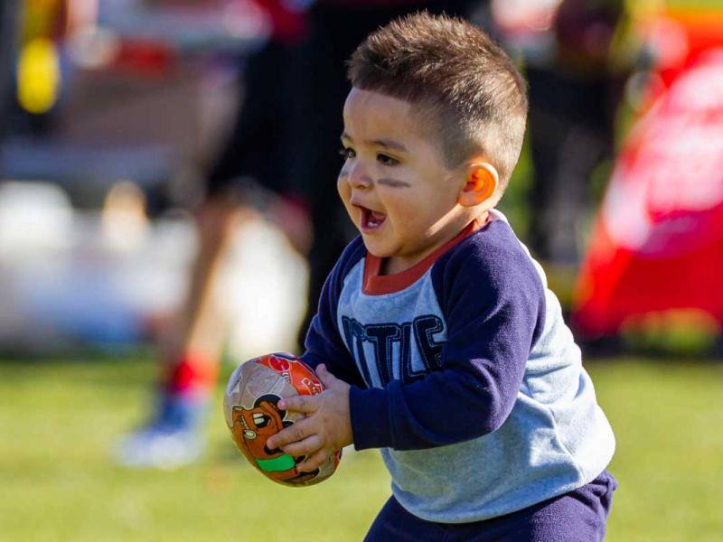Boy in Purple Long Sleeves Shirt and Purple Pants Holding Brown Football
