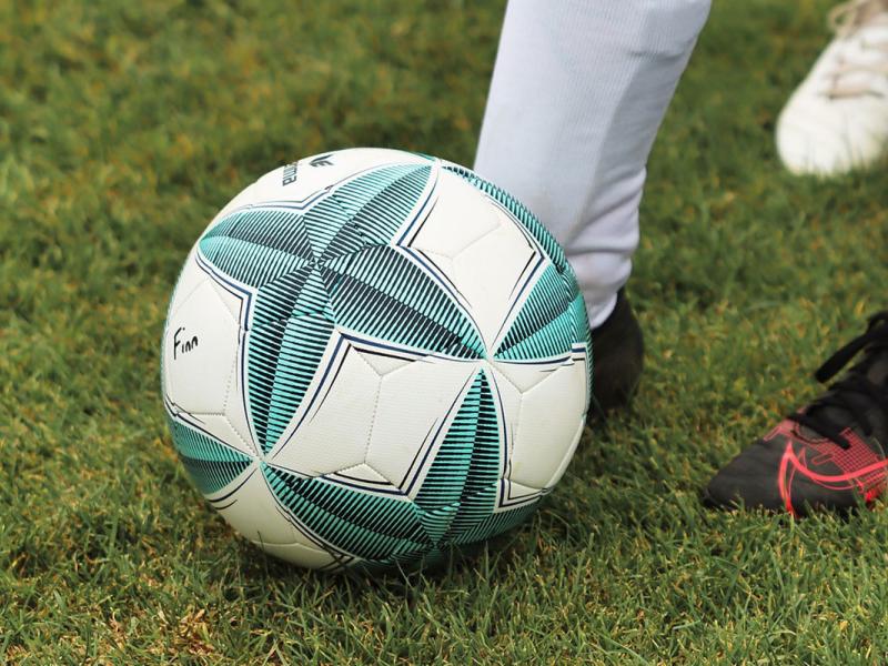 Photo of a soccer ball being kicked.