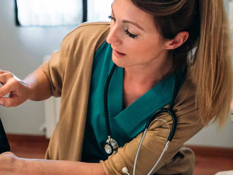Female doctor showing to female senior patient an x-ray on a handheld tablet during