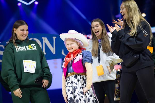 Penelope Ciancaglini walks the runway during a THON™ fashion show while students cheer her on.