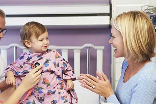 A nurse listens to a baby's heart while her mother watches