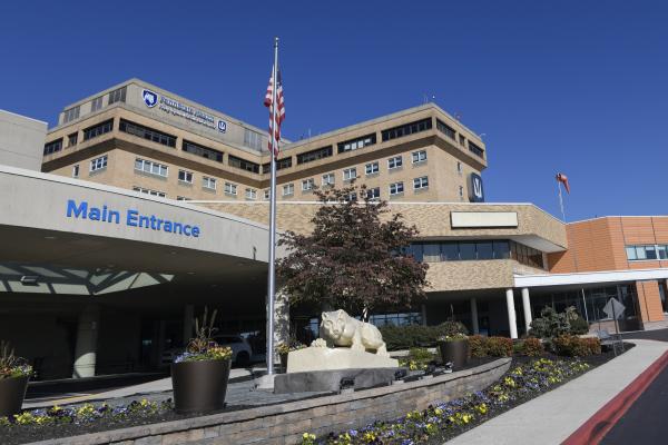 A statue of the Penn State Nittany Lion sits out front of the exterior of Penn State Health Holy Spirit Medical Center located in Cumberland County, Pennsylvania. Background: bright, blue, cloudless sky