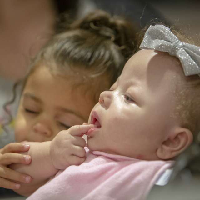 Ramiah Martin sits reclined in a stroller; her sister sits beside her, placing her hand on Ramiah's arm.