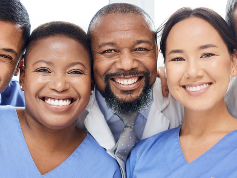 Group of health care workers gather and smile.