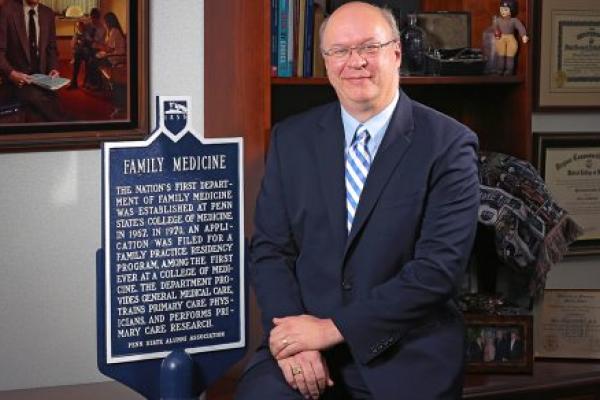 Mack Ruffin IV, MD, MPH, sits for a professional portrait next to an historical marker about the nation's first Department of Family Medicine being established at Penn State College of Medicine in 1967.