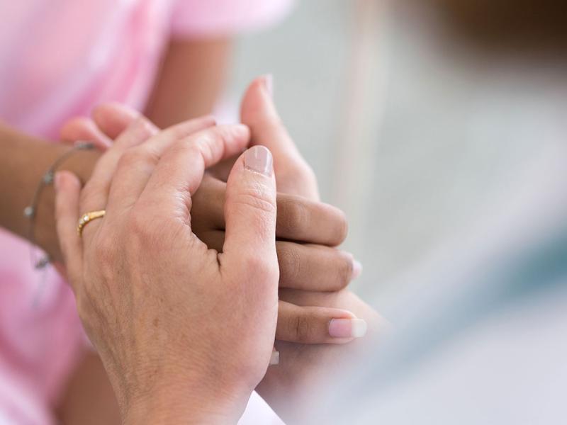 A person holds a woman’s hand.