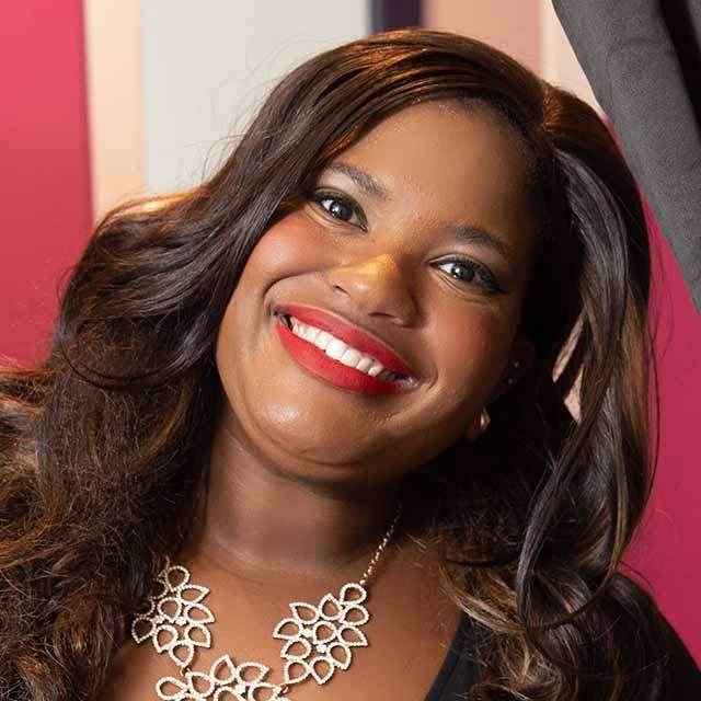 A closely cropped head and shoulders photo of Alixandra Moyer, smiling with her head tilted to the right.