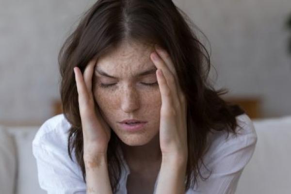 A woman touches the temples of her aching head.