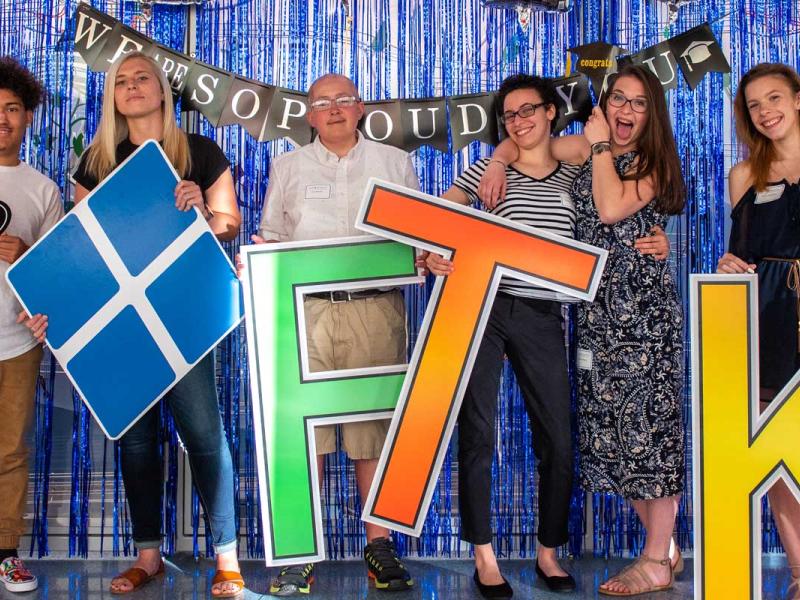 Eight people standing beside each other displaying the Four Diamonds logo and FTK letters