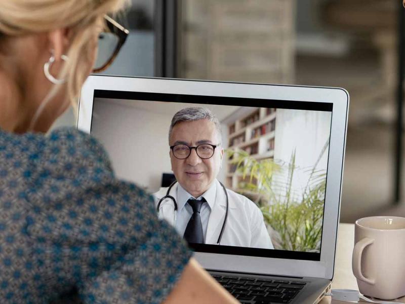 Young woman talking with doctor on laptop computer.