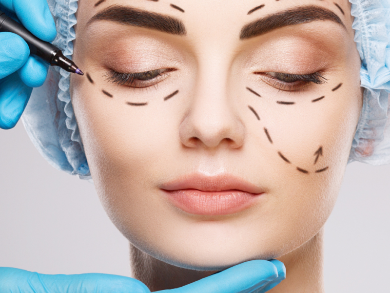 Woman wearing surgical cap as provider prepares for cosmetic procedure.