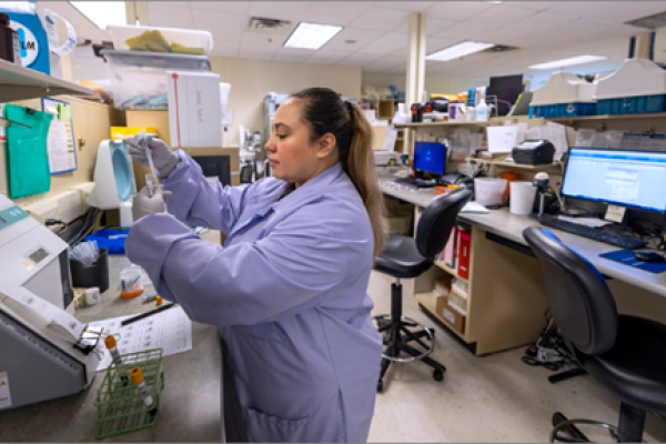 A medical professional in blue scrubs works with some machinery